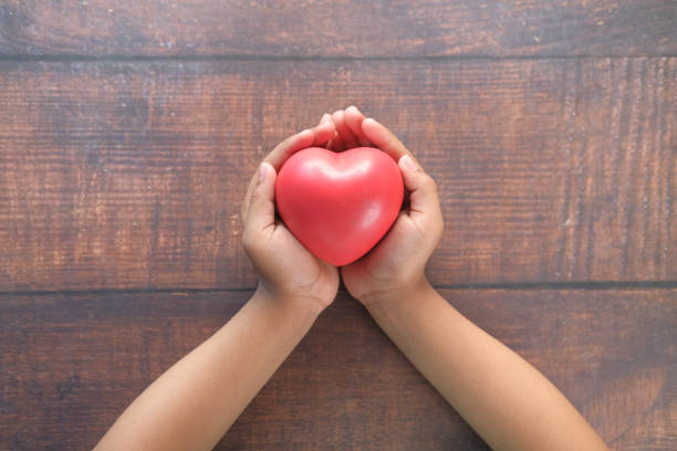 istock child hand holding red heart on wooden table 1322807031