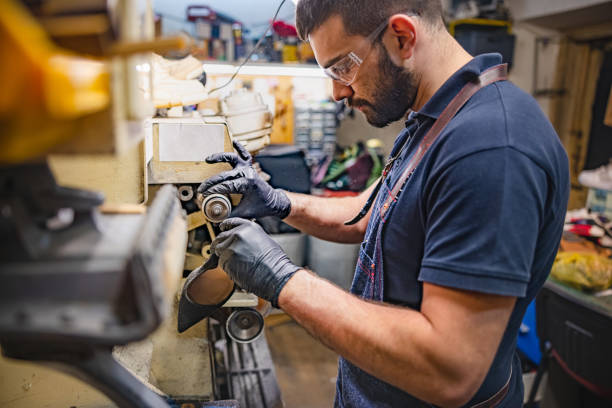 istock Young man wearing protective gloves and eyewear working on shoe sole with grinder 1322807823