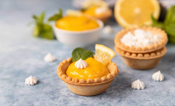 istock Mini tarts with lemon curd, mini meringue, lemon slices and mint on blue concrete background. 1322810443