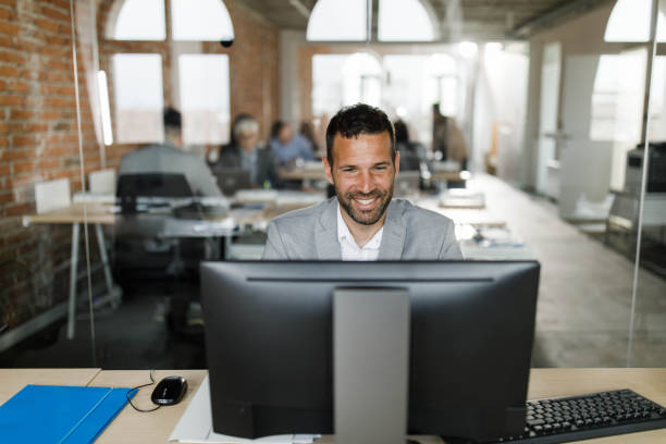 istock Happy businessman working on desktop PC at corporate office. 1322811689