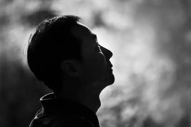 Photo of Black and white image of a man looking up with blurred background. Hope concept.