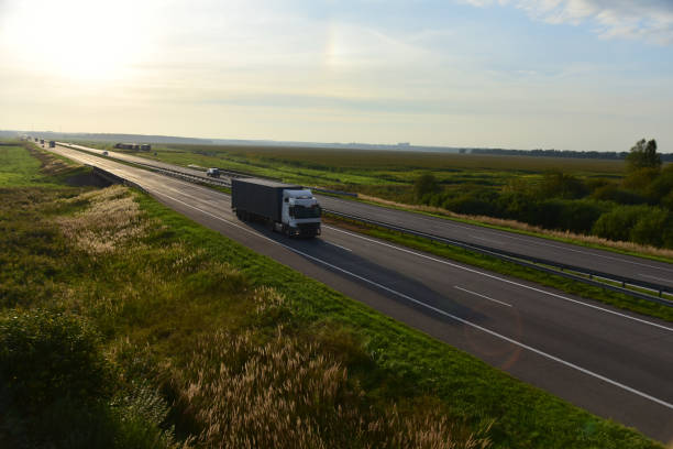 istock Semi truck transporting sea container on highway on sunset background. Shipping Containers Delivery, Maritime Services and Transport logistics. 1322814058