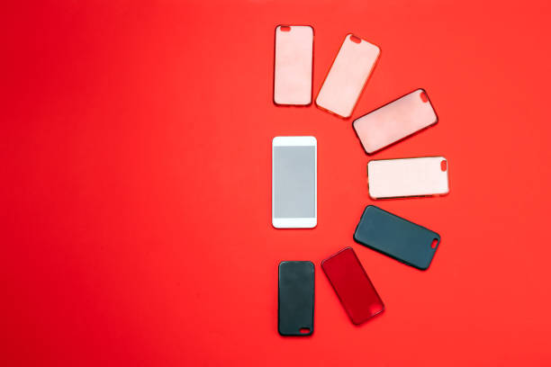 Choice of multicolored plastic back covers for mobile phones on red background with a smart phone on the side
