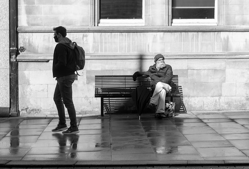 Bearded man on a bench in Cambridge, England, UK.  He has a long beard during partial lockdown in May, 2021.