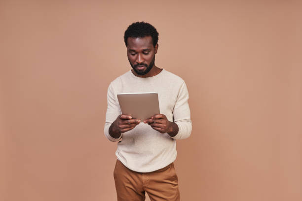 istock Confident young African man in casual clothing using digital tablet 1322820612