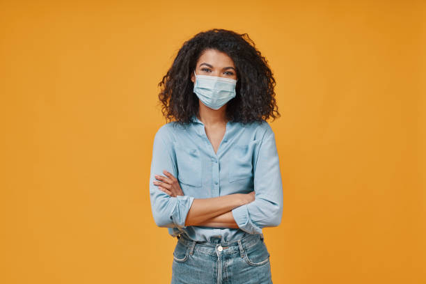 istock Beautiful young African woman in protective face mask looking at camera 1322820861