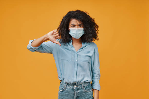 istock Frustrated young African woman in protective face mask gesturing and looking at camera 1322821611