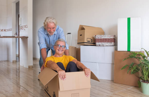 istock Happy senior couple white haired having fun during relocation, excited for the new beginning.  Moving boxes on the floor, empty apartment 1322821913