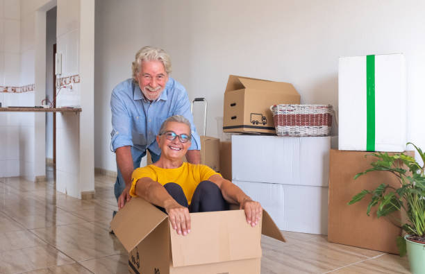 istock Happy senior couple white haired having fun during relocation, excited for the new beginning.  Moving boxes on the floor, empty apartment 1322821924