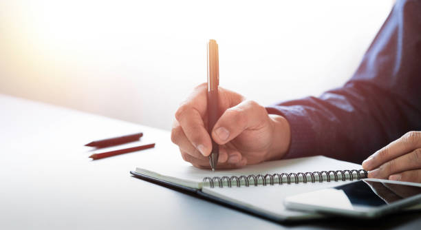 istock Businessman hand holding writing pen memo into notebook paper on table desk office. Workplace for business and student, writer with copy space. business working and learning education concept. 1322824066