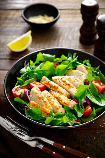 istock Grilled chicken breast and salad. Fresh vegetable salad with tomato, arugula, spinach and grilled chicken meat in bowl, healthy food. 1322824157