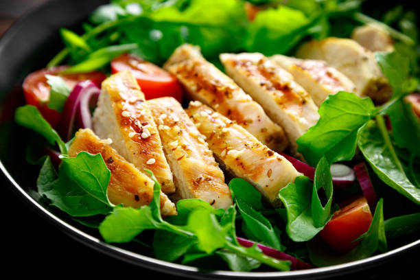 grilled chicken breast and salad. fresh vegetable salad with tomato, arugula, spinach and grilled chicken meat in bowl, healthy food. - arugula salad herb organic imagens e fotografias de stock