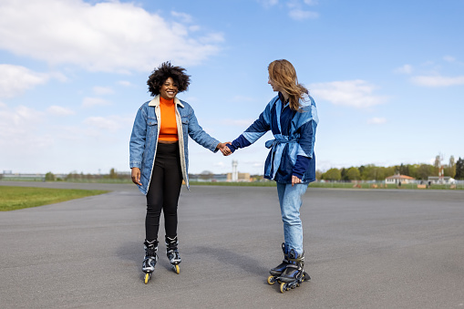 Women friends skating in Tempelhof park. Females roller skating on airport runway in berlin.