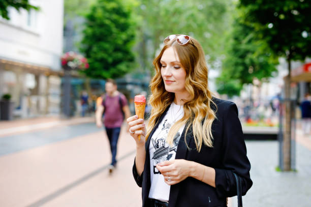 giovane donna d'affari che mangia gelato. felice donna sola in città nella soleggiata giornata estiva, pausa per il pranzo tra un incontro e l'altro. - starbucks women walking restaurant foto e immagini stock