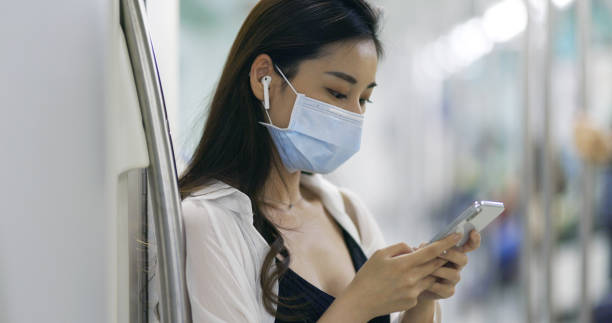 마스크를 쓰고 스마트폰과 이어폰을 사용하는 아시아 여성 - human lung audio 뉴스 사진 이미지