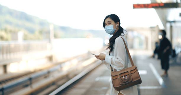 마스크를 쓰고 스마트폰과 이어폰을 사용하는 아시아 여성 - human lung audio 뉴스 사진 이미지