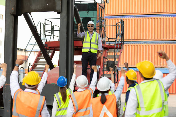 istock warehouse boss engineer standing on crane car with factory workers raise hand for congratulations in containers warehouse storage 1322827475
