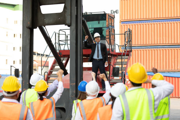 istock warehouse boss engineer standing on crane car with factory workers raise hand for congratulations in containers warehouse storage 1322828026