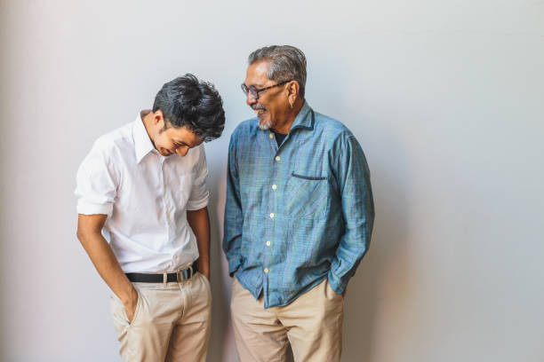 portrait of asian senior father and his adult son having fun together and standing on gray backgrounds - asian and indian ethnicities imagens e fotografias de stock