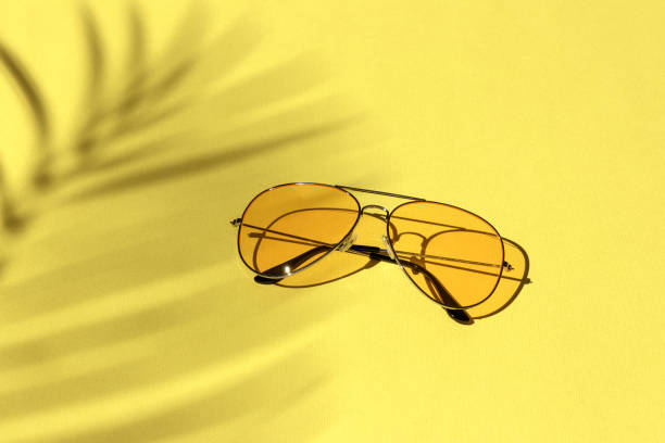istock yellow sunglasses on a pastel background under a palm tree shadow. leisure, travel and entertainment concept with copy space 1322831472