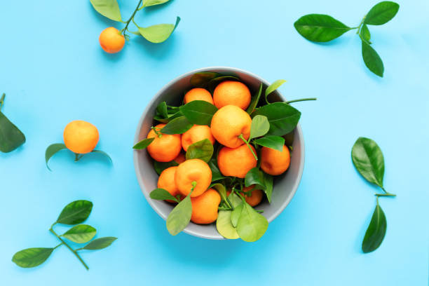 istock Clementines with leaves on a blue background. Flat lay, top view. 1322832428