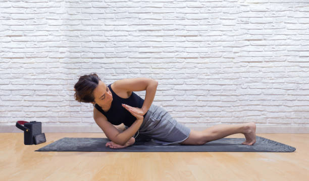 girl practicing yoga in a brightly lit room, using a guided yoga class via mobile phone and speakerphone. - brightly lit audio imagens e fotografias de stock