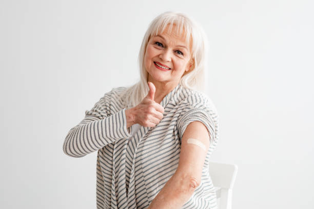 istock Happy Vaccinated Mature Woman Gesturing Thumbs-Up Over White Background 1322838374