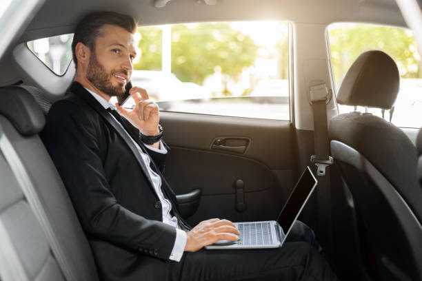 istock Cheerful CEO with laptop talking on phone in car 1322838713