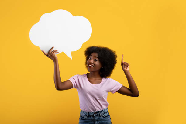 istock Inspired african american lady having idea, holding blank speech bubble and pointing finger up, yellow background 1322838780
