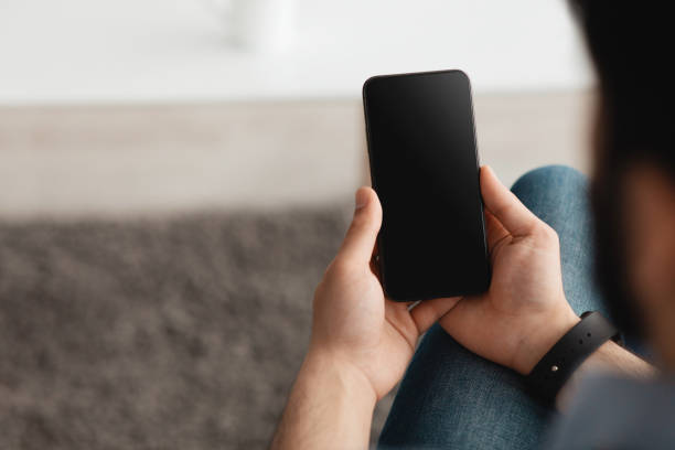 istock People and technology concept. Over the shoulder view of guy using smartphone with blank screen for mockup 1322838938