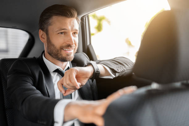 istock Handsome bearded man in suit sitting in taxi, checking time 1322839773