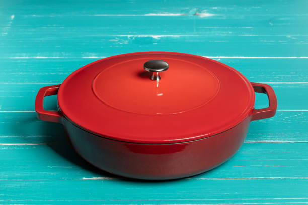 istock Red enameled pan with two handles on turquoise table 1322840284
