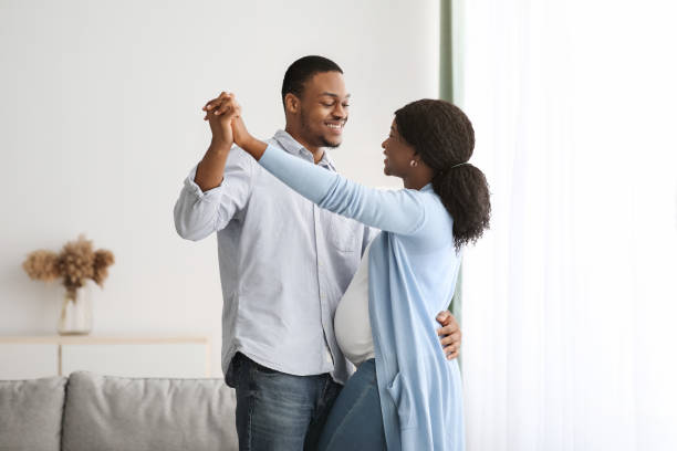 Romantic black pregnant couple dancing at home