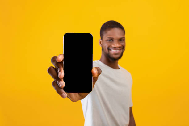 istock Cellphone display mockup. Happy black man showing smartphone with empty screen, recommending mobile app 1322843030