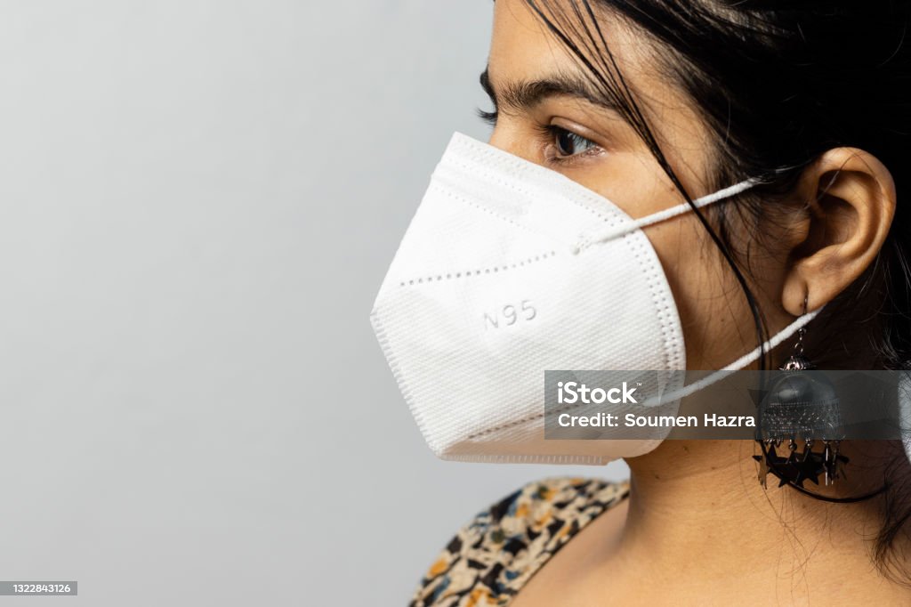 Woman in N 95 nose mask Close up side face of an Indian woman wearing N 95 mask on white background N95 Face Mask Stock Photo