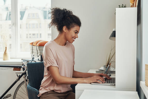 istock Beautiful young African woman using laptop and smiling 1322843884