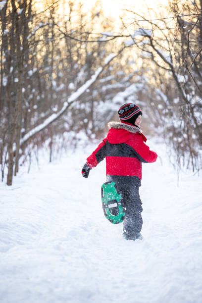 little boy rakiety śnieżne w proszku snow outdoors w zimie podczas zachodu słońca - snowshoeing snowshoe child winter zdjęcia i obrazy z banku zdjęć