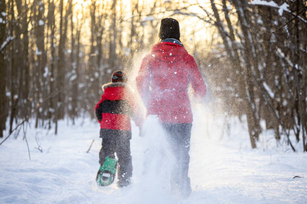 Mother and Son Running with Snowshoes in Powder Snow Outdoors in Winter during sunset Mother and Son Running with Snowshoes in Powder Snow Outdoors in Winter during Sunset snowshoeing snow shoe red stock pictures, royalty-free photos & images