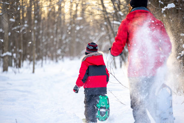 Mother and Son Running with Snowshoes in Powder Snow Outdoors in Winter during sunset Mother and Son Running with Snowshoes in Powder Snow Outdoors in Winter during Sunset snowshoeing snow shoe red stock pictures, royalty-free photos & images
