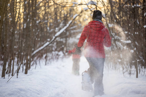 Mother and Son Running with Snowshoes in Powder Snow Outdoors in Winter during sunset Mother and Son Running with Snowshoes in Powder Snow Outdoors in Winter during Sunset snowshoeing snow shoe red stock pictures, royalty-free photos & images