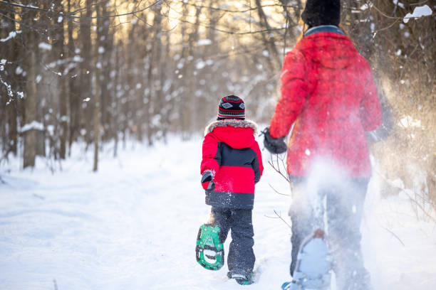 madre e figlio che corrono con le ciasli in polvere neve all'aperto in inverno durante il tramonto - winter snowshoeing running snowshoe foto e immagini stock