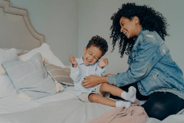 femme afro-américaine s’amusant avec un petit fils adorable à la maison - tickling photos et images de collection