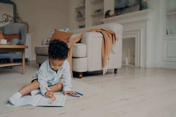 istock Little mixed race kid boy drawing in coloring book while spending leisure time alone at home 1322845934