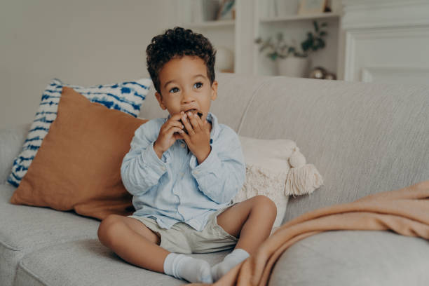 istock Hungry cute afro american boy eating cupcake while spending time at home 1322845945