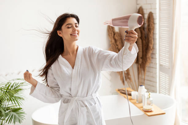 istock Joyful Lady Drying Hair Using Hairdryer Standing In Bathroom 1322847463