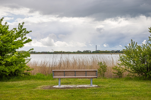A public bench with a view over the water in a public park in Ishøj a suburb south of Copenhagen.