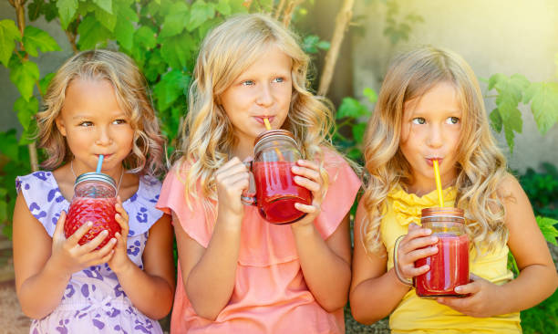 Girls drinking watermelon smoothie outdoors. Three Caucasian girls drinking watermelon smoothie outdoors. Summertime leisure concept. watermelon juice stock pictures, royalty-free photos & images