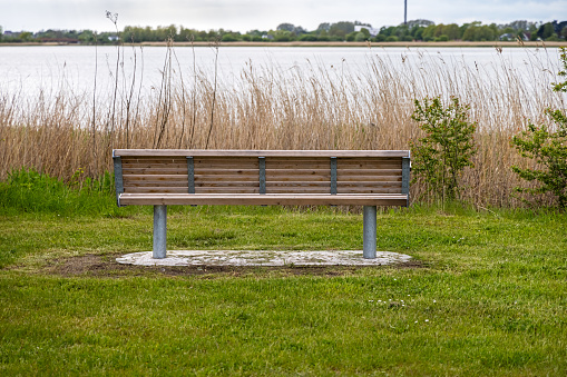 Autumnal sunset at the lake. Lakeshore with a bench and walkway. Empty bench at the park. Nobody, selective focus