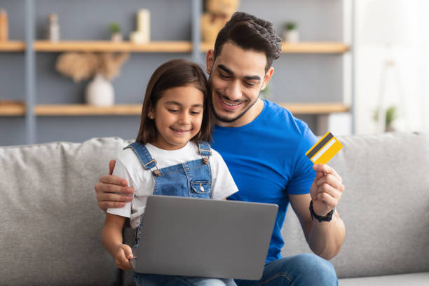 famille utilisant un ordinateur et une carte de crédit à la maison - internet e commerce credit card retail photos et images de collection