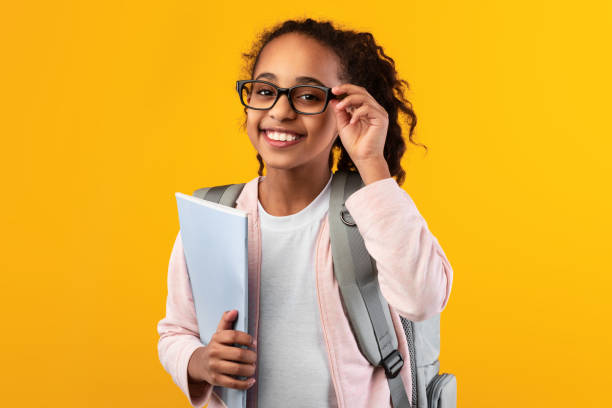 istock Cheerful young black girl holding textbooks looking at camera 1322850099